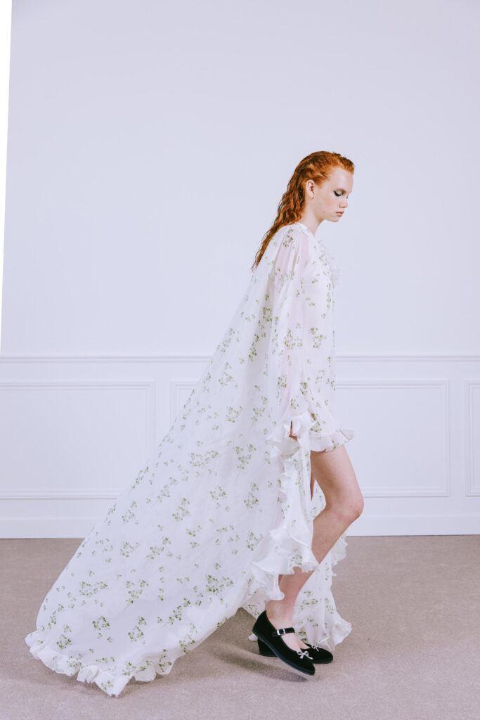 A relaxed white silk dress with long sleeves, a V-neckline, and tiered design details.