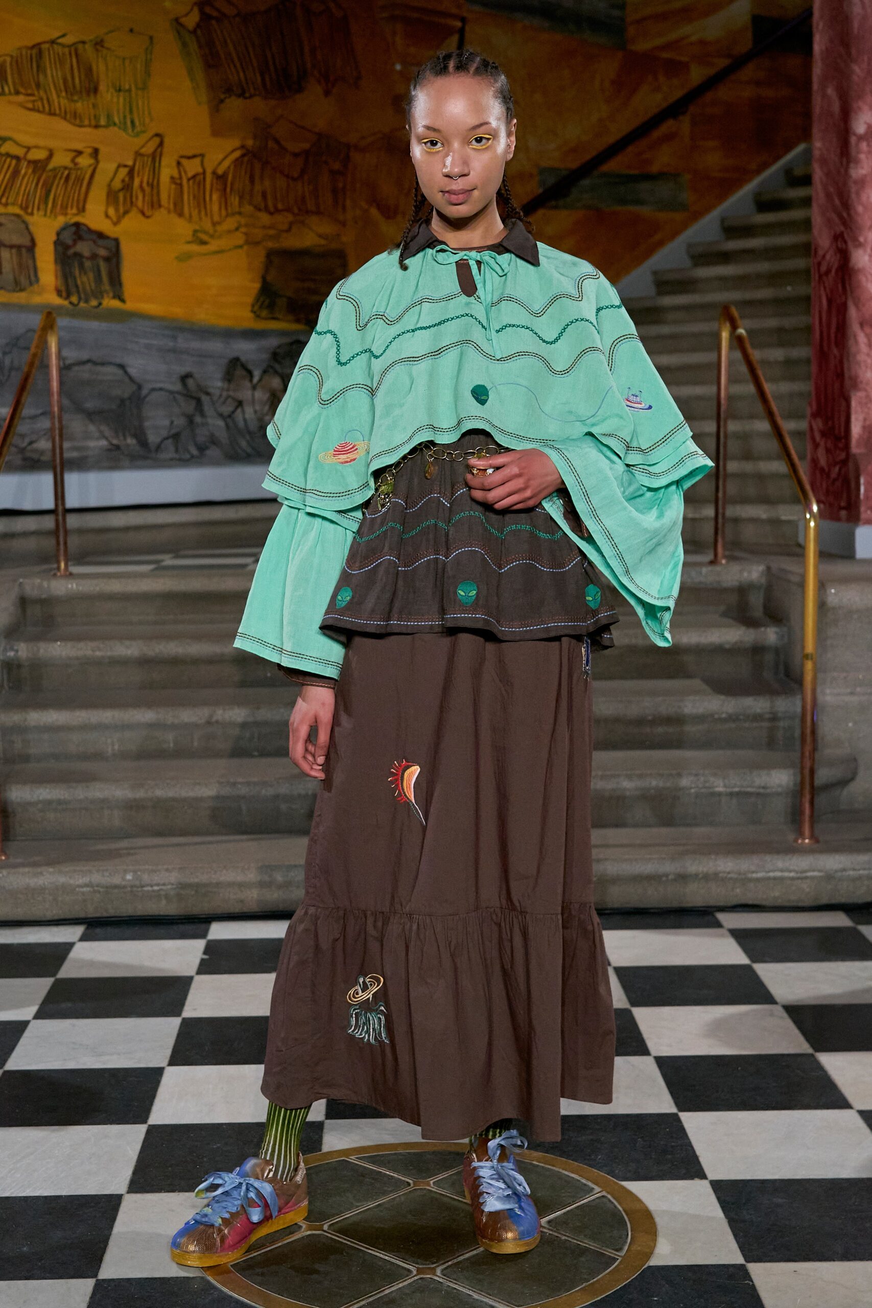 A relaxed brown tiered dress paired with a long-sleeve green cape featuring a collared design.