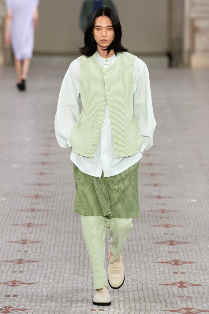 A relaxed green pleated vest worn over a white collared shirt with matching pants.