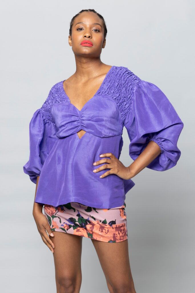 A fitted purple silk top with long sleeves and a V-neck, paired with a floral mini skirt.