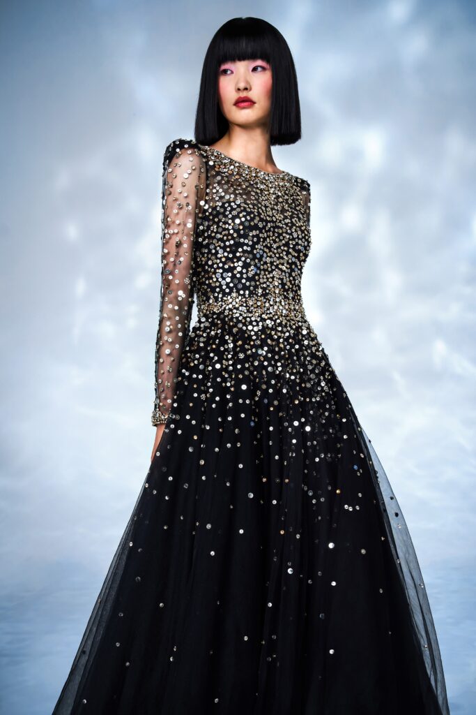 A fitted black gown with long sleeves, high neckline, and intricate embroidery details.