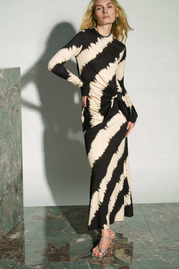 A fitted long-sleeve black and white dress with a V-neckline and asymmetric design.