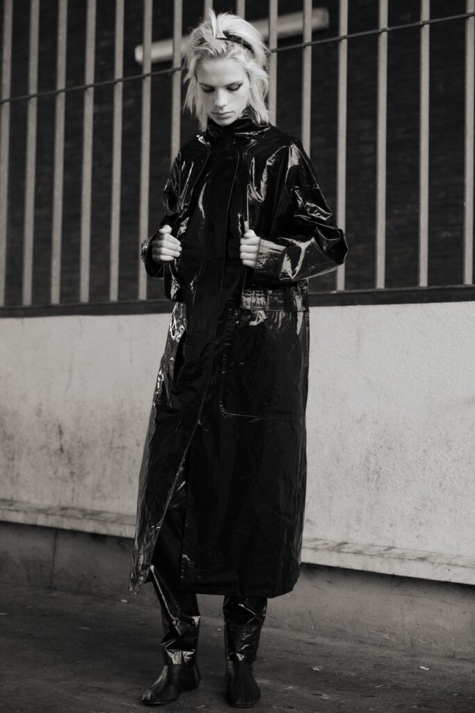 A fitted black leather coat with long sleeves and a zippered front.