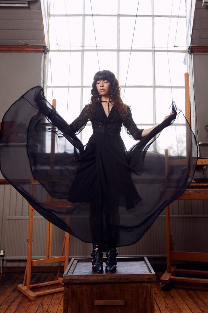 A fitted black silk long-sleeve dress with a V-neckline and layered design.