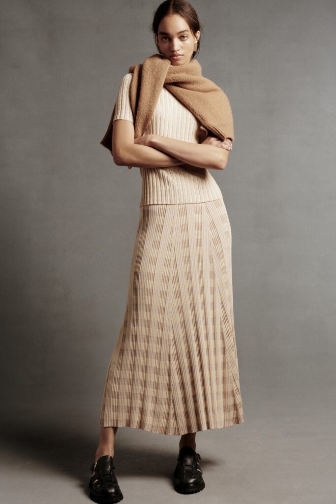 A fitted beige top with short sleeves paired with a pleated tiered skirt.
