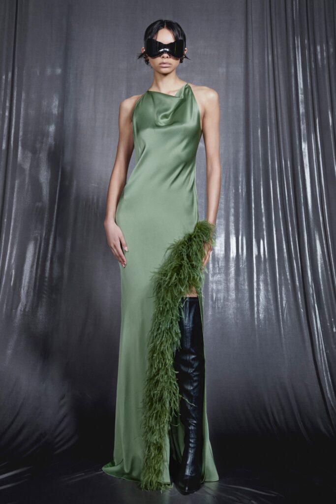 A fitted green silk sleeveless dress with a high neckline and asymmetric design detail.