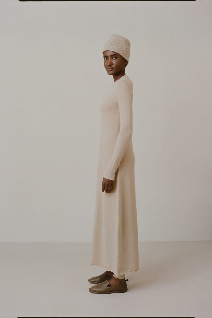 A fitted beige wool maxi dress with long sleeves and a high neckline.