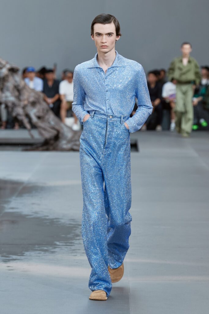 A fitted blue sequined jumpsuit with long sleeves and a collared neckline.