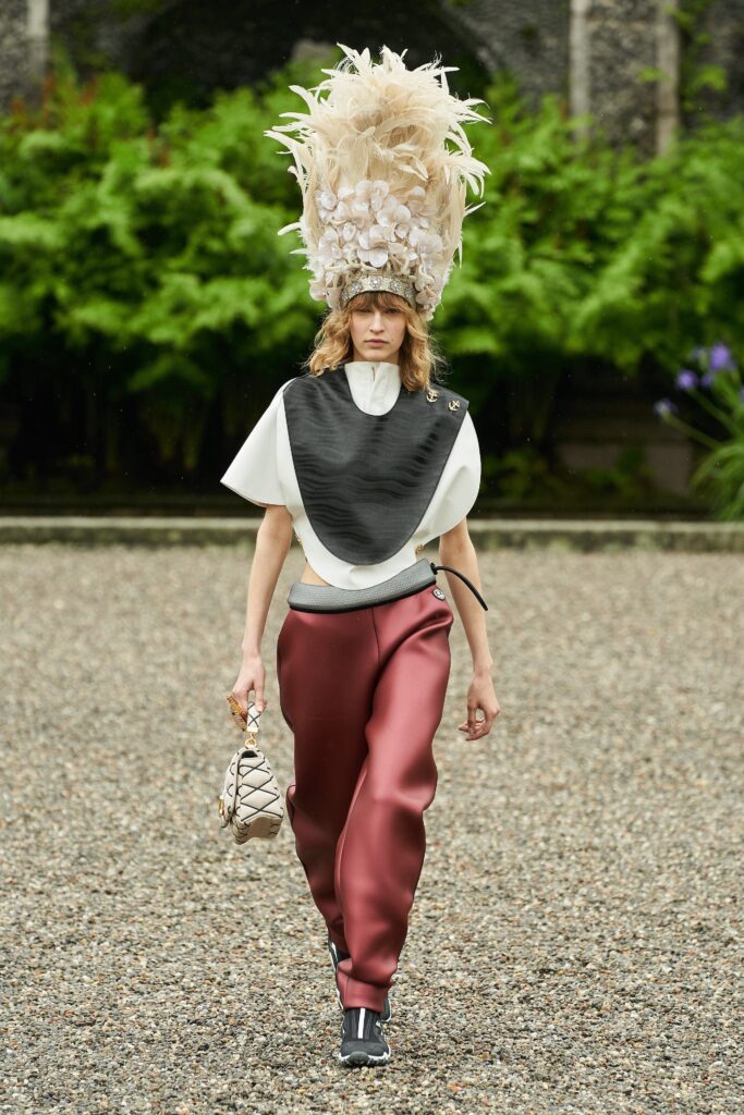 A fitted black silk top with short sleeves and high-neck paired with fitted red wide-leg pants.