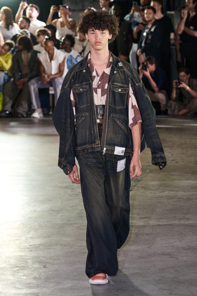 A relaxed fit blue denim jacket layered over a white shirt with matching denim pants.