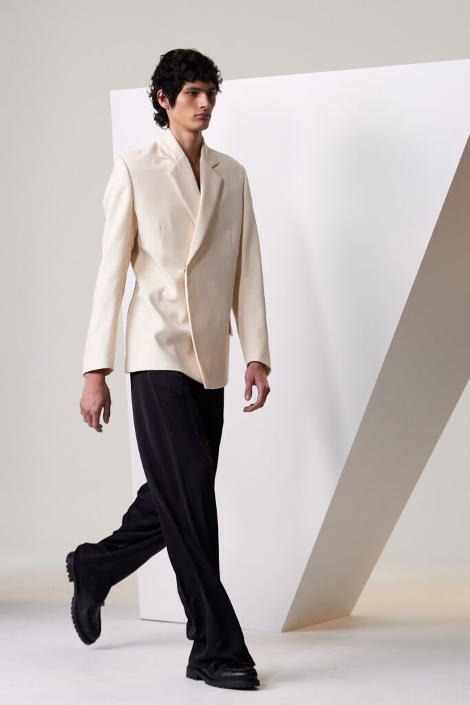 A tailored white blazer with long sleeves paired with straight-leg black pants.