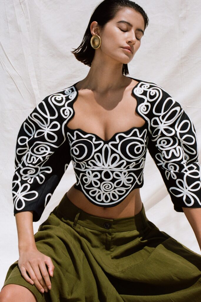 A fitted black embroidered top with short sleeves paired with a green skirt.