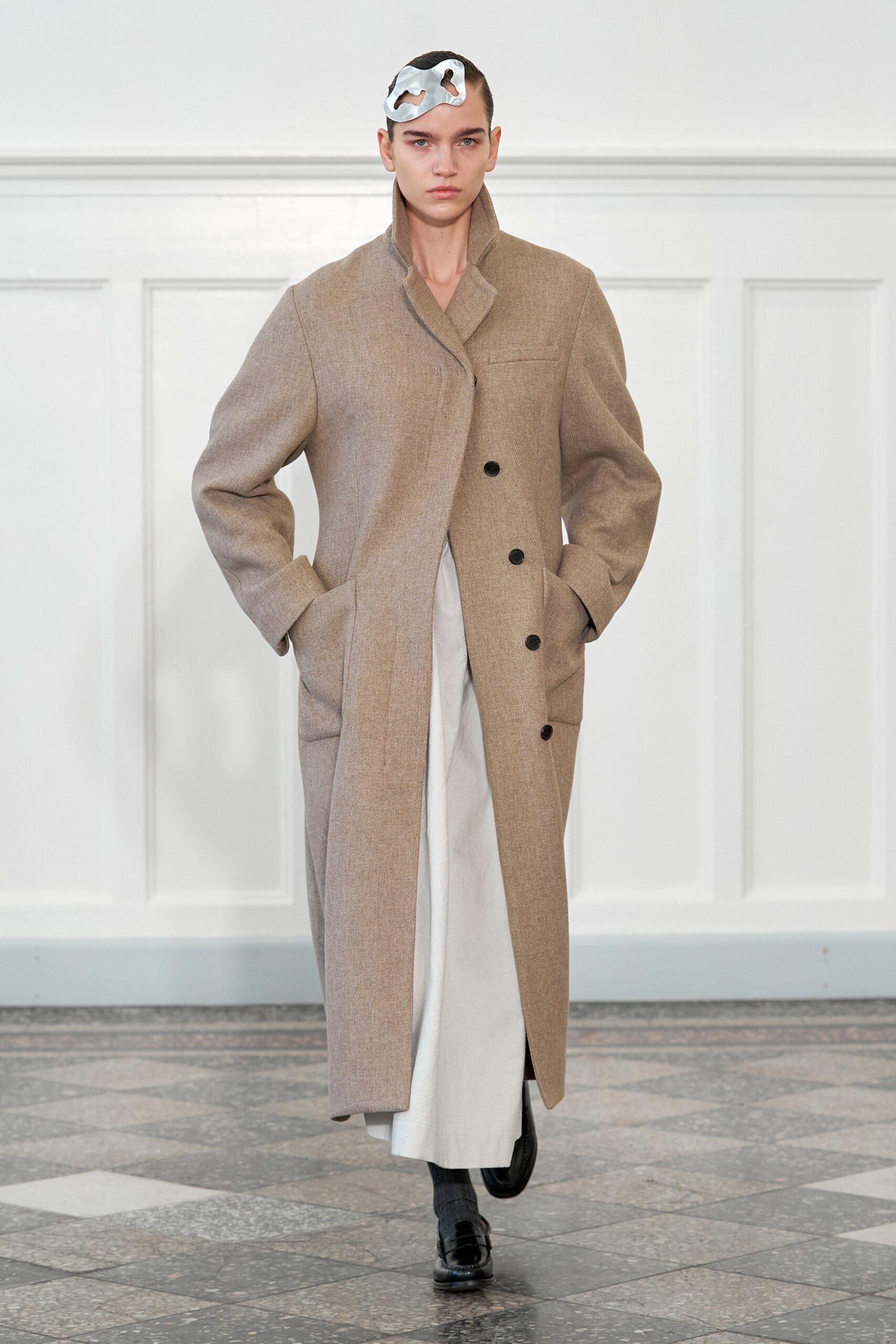 A relaxed beige wool coat with long sleeves and a collared design, featuring button details.