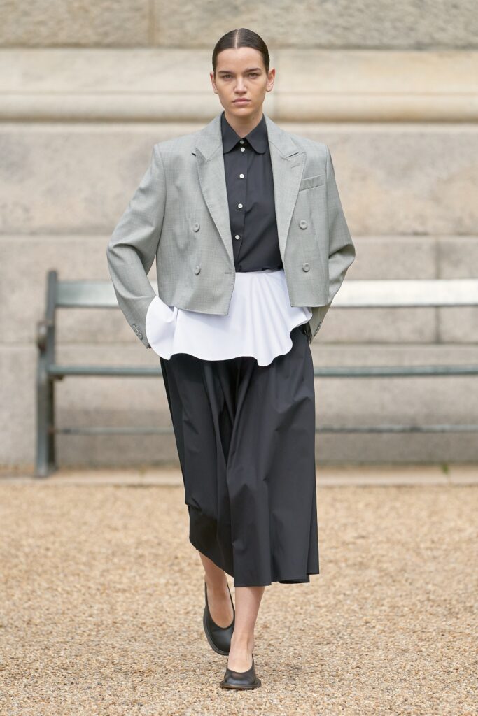 A relaxed gray blazer over a layered black dress with a white accent.