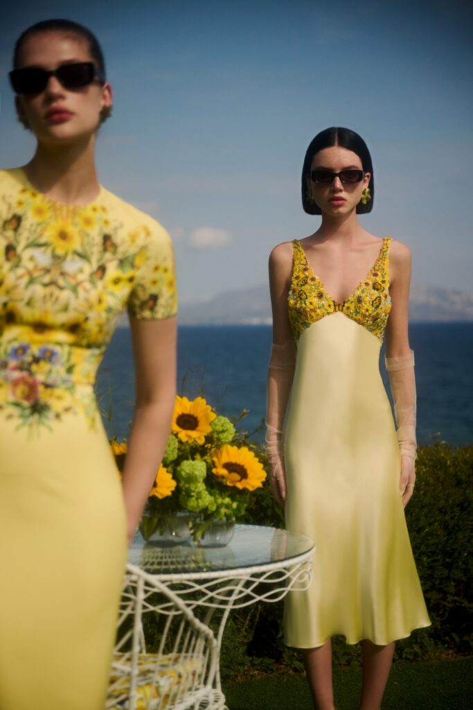 A fitted yellow silk dress with a V-neckline and flared silhouette, adorned with floral details.