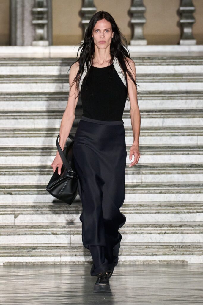 A fitted black silk sleeveless top paired with an asymmetric black skirt.