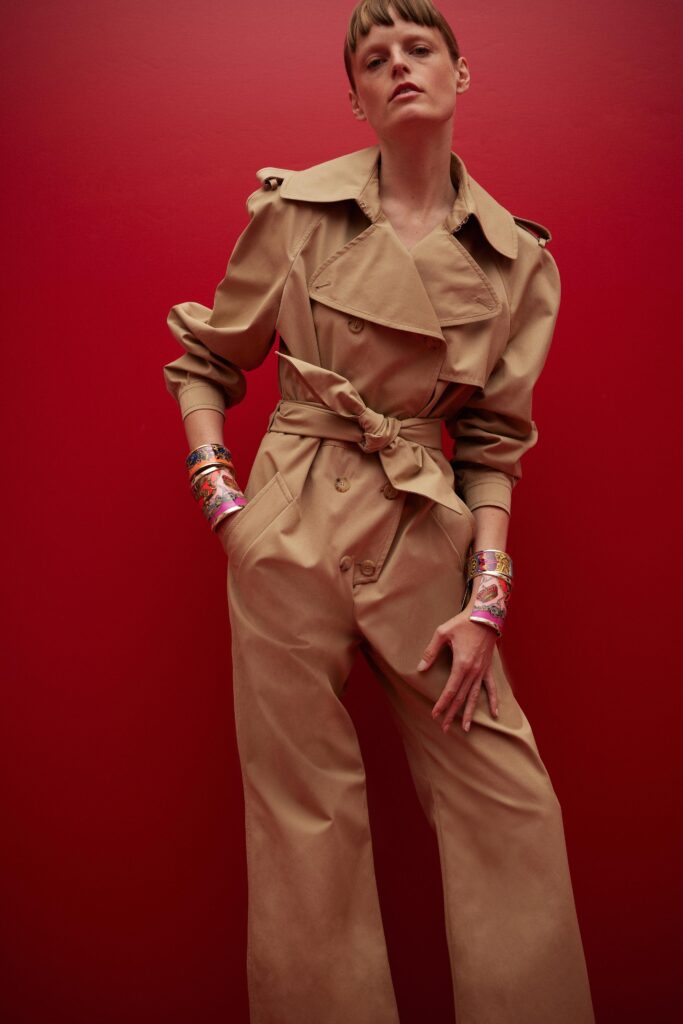 This relaxed trench coat in beige features a classic long-sleeve silhouette with a structured collar. The belted waist adds definition, creating a harmonious balance between functionality and style.