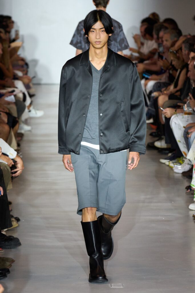 A relaxed black jacket paired with gray shorts, featuring a V-neckline and zippered detail.