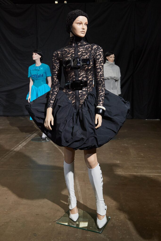 A fitted black lace dress with a high neckline and flared silhouette.