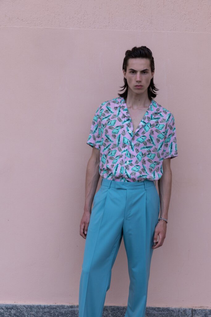 A relaxed pink printed shirt paired with blue pants, featuring a collared neckline and short sleeves.