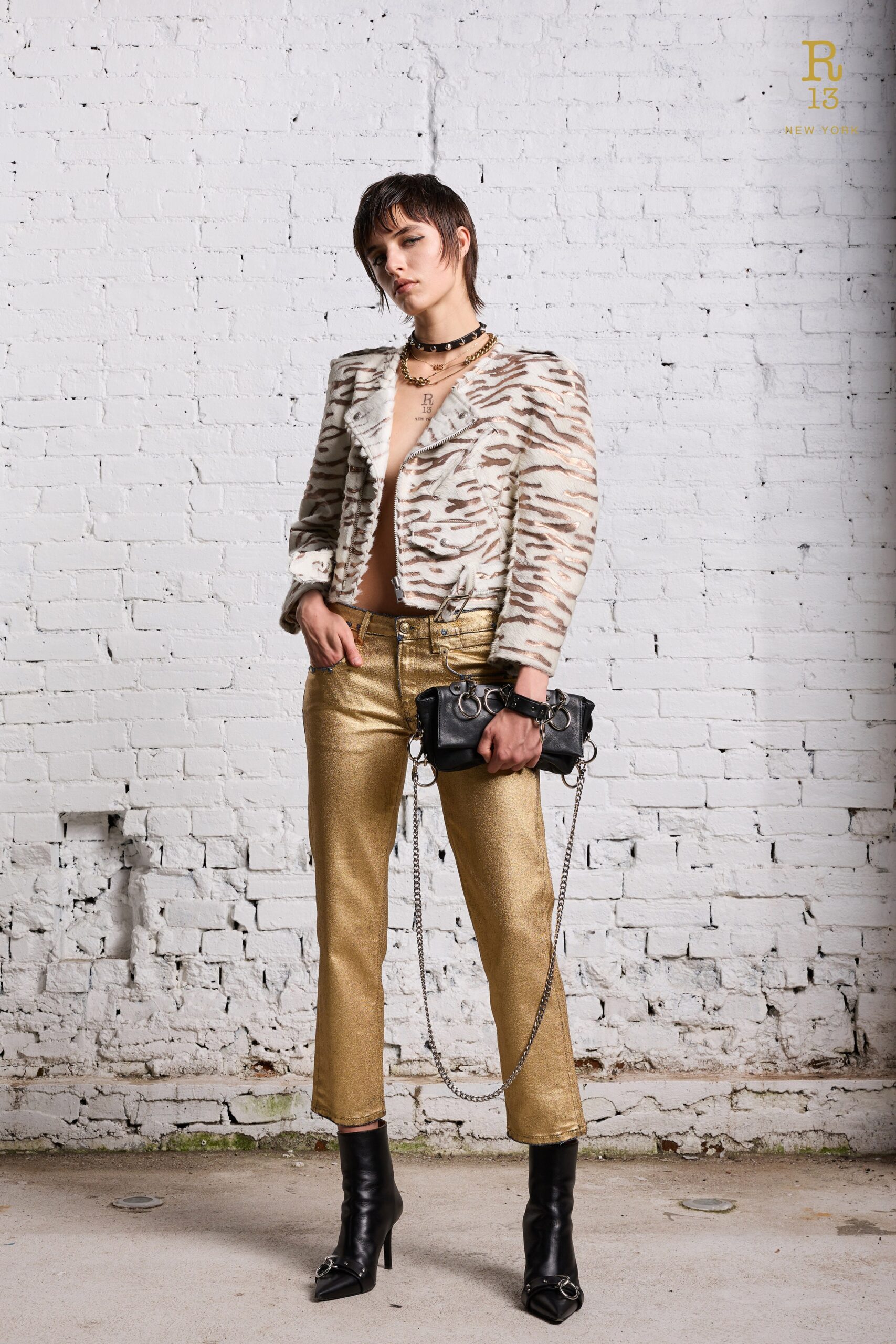 A fitted beige striped jacket with long sleeves paired with fitted gold metallic pants.