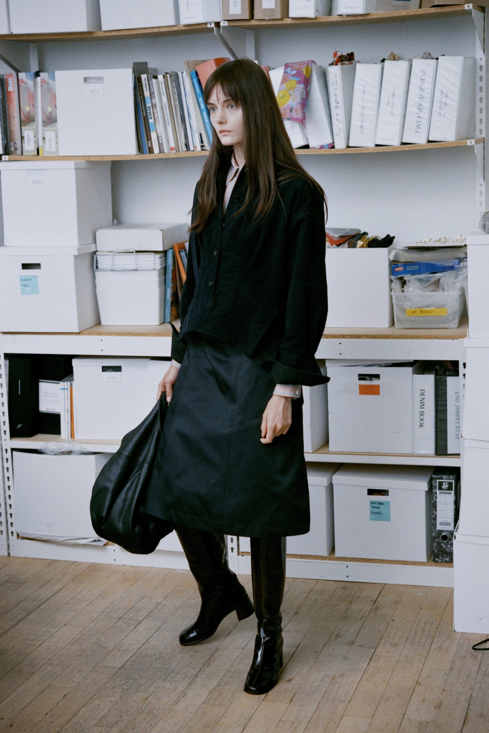 A relaxed black long-sleeve collared top paired with an asymmetric black skirt.