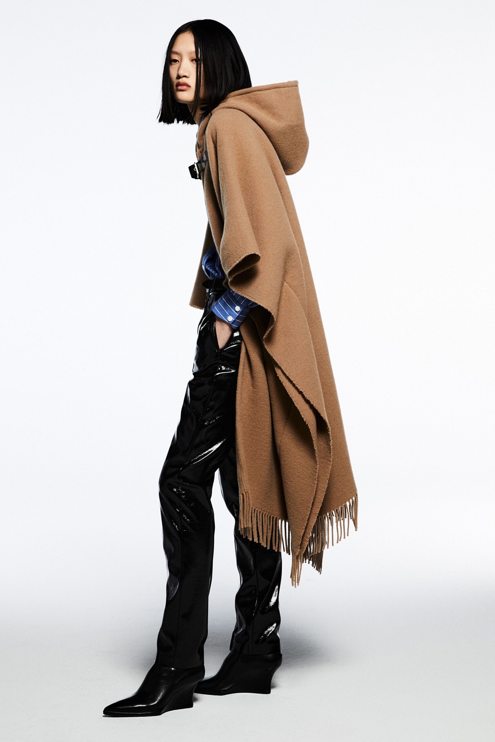 A fitted brown wool poncho with a hood paired with sleek black leather pants.