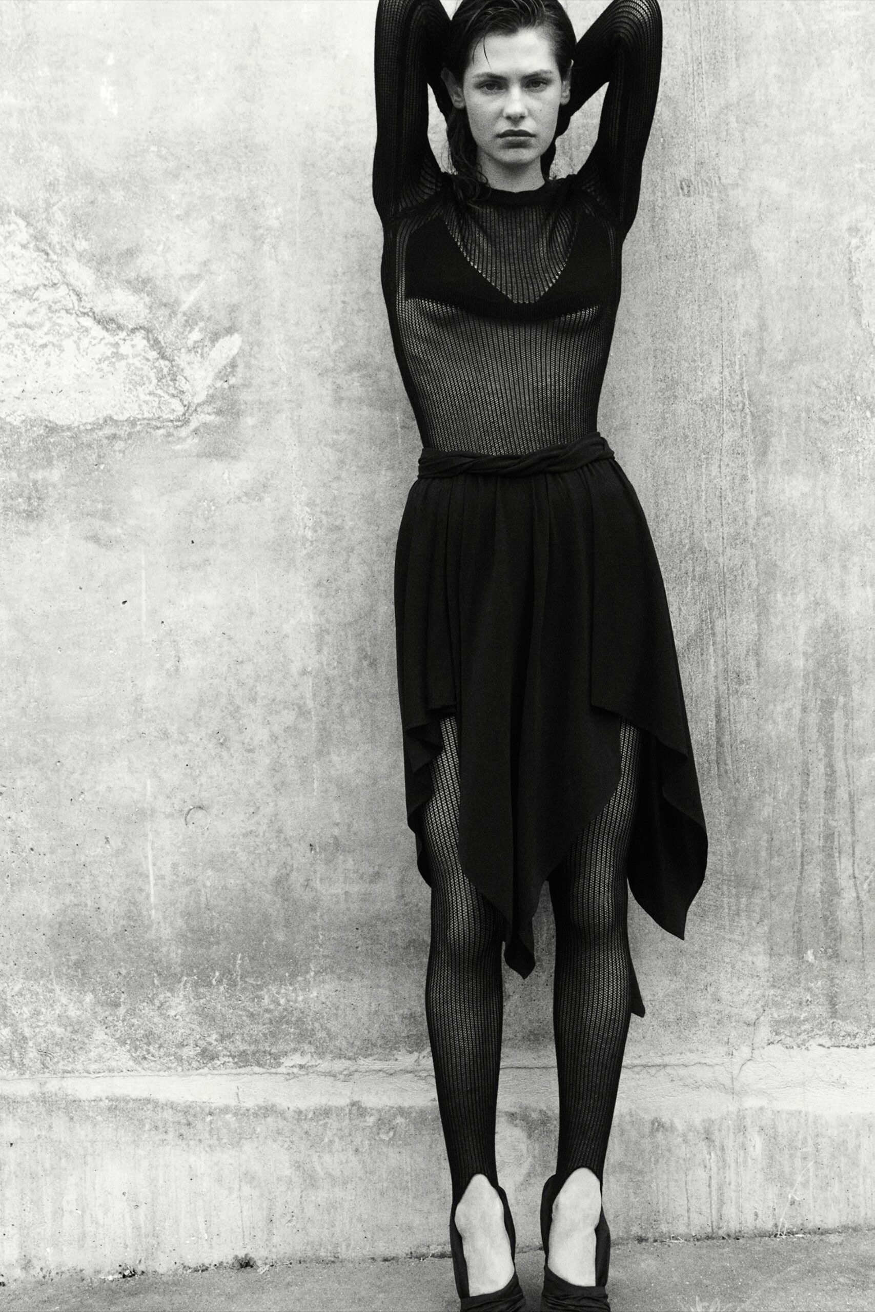 A fitted black sleeveless dress with a V-neckline and asymmetric design.