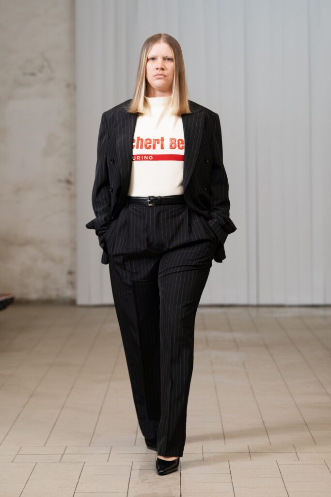 A tailored black suit paired with a white long-sleeve top featuring a bold graphic print.