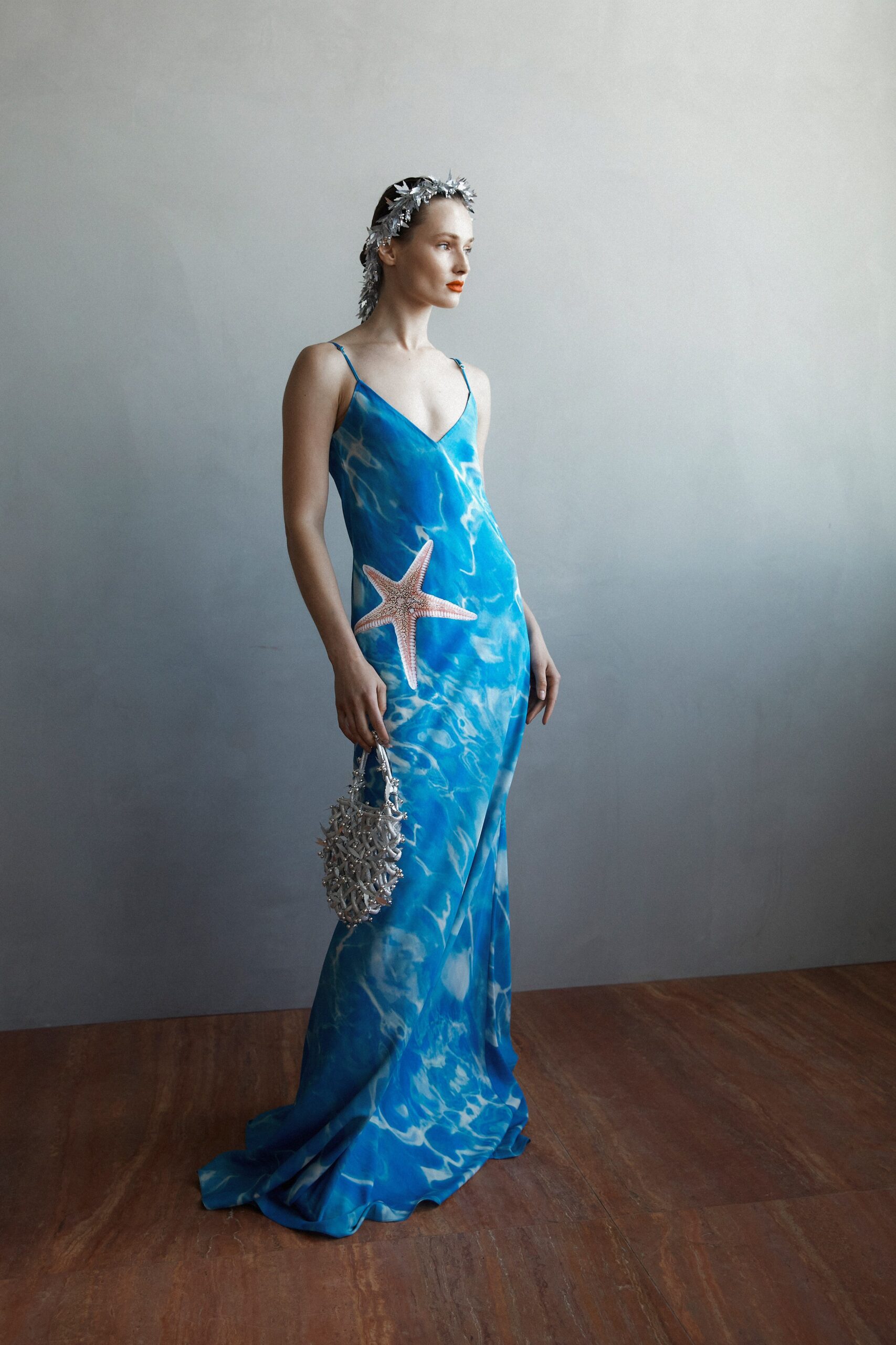 A fitted blue silk sleeveless dress with a V-neckline and a printed design.