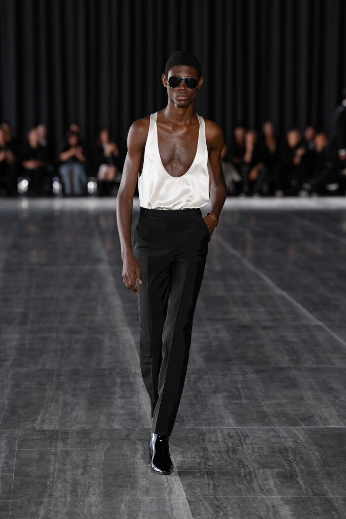A fitted white silk sleeveless top with a V-neck and straight-leg black pants.