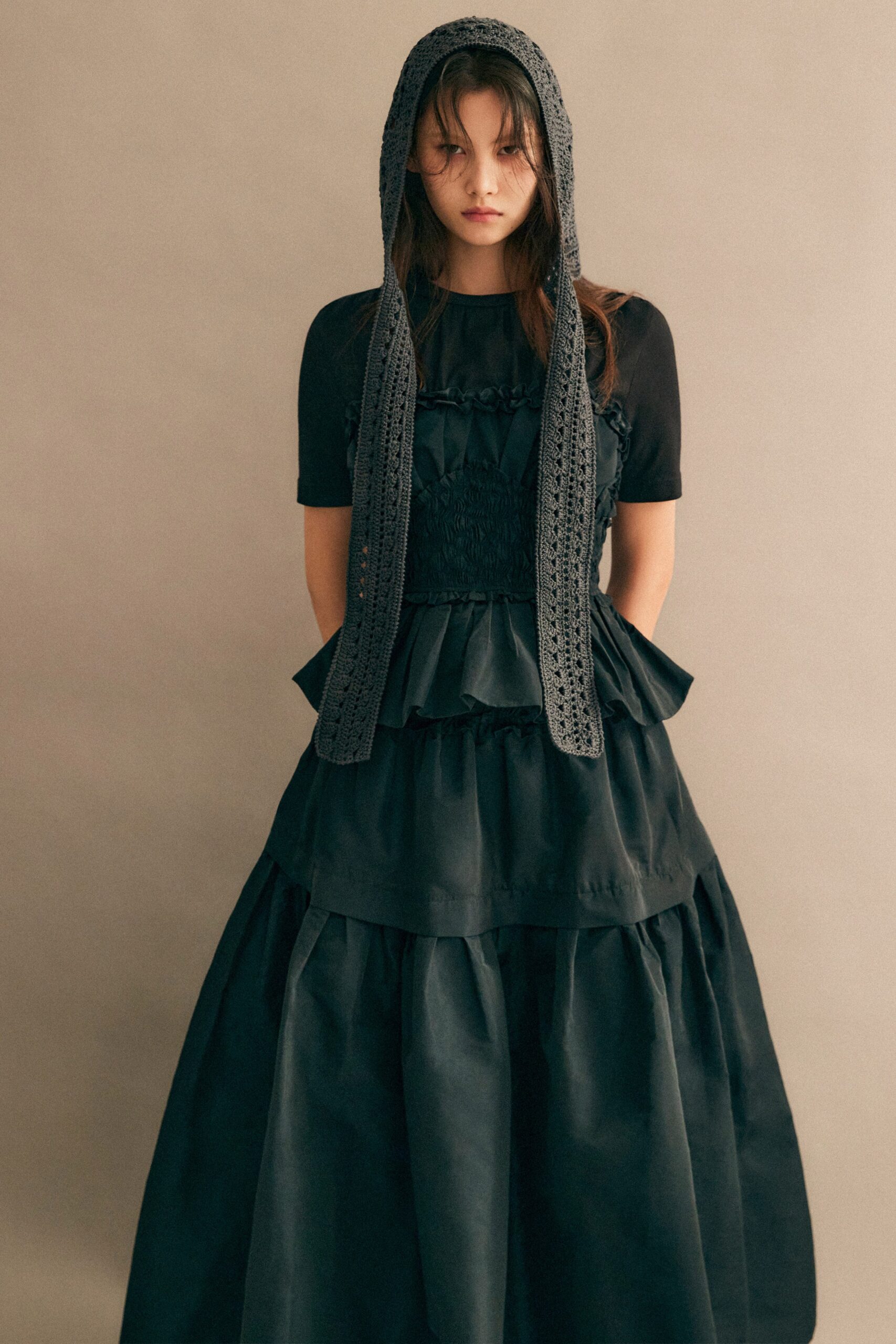 A fitted black cotton sleeveless dress with a high neckline and tiered design.