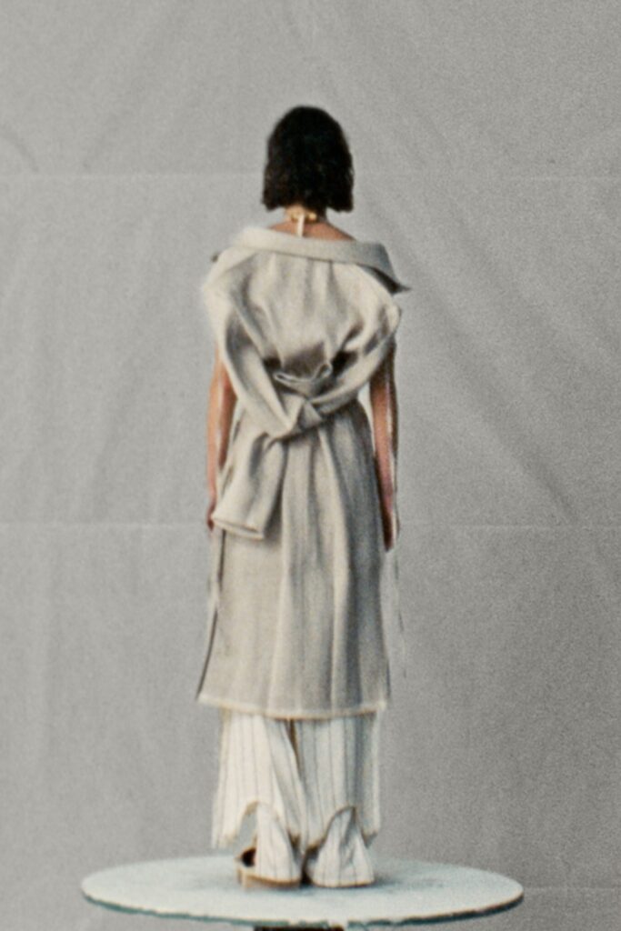 A relaxed gray sleeveless dress with a high neckline and layered design details.