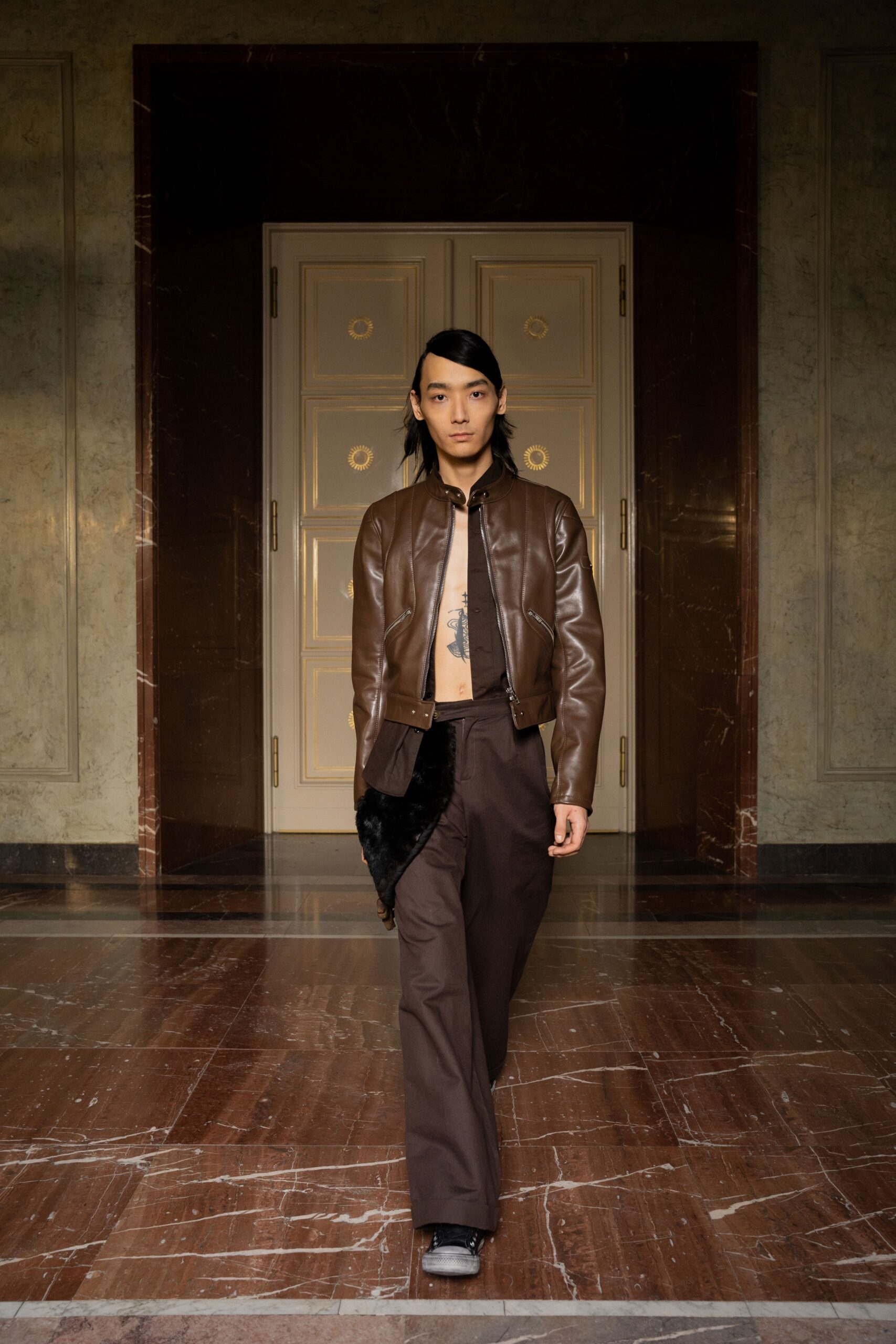A fitted brown leather jacket paired with straight-leg cotton pants for a stylish look.