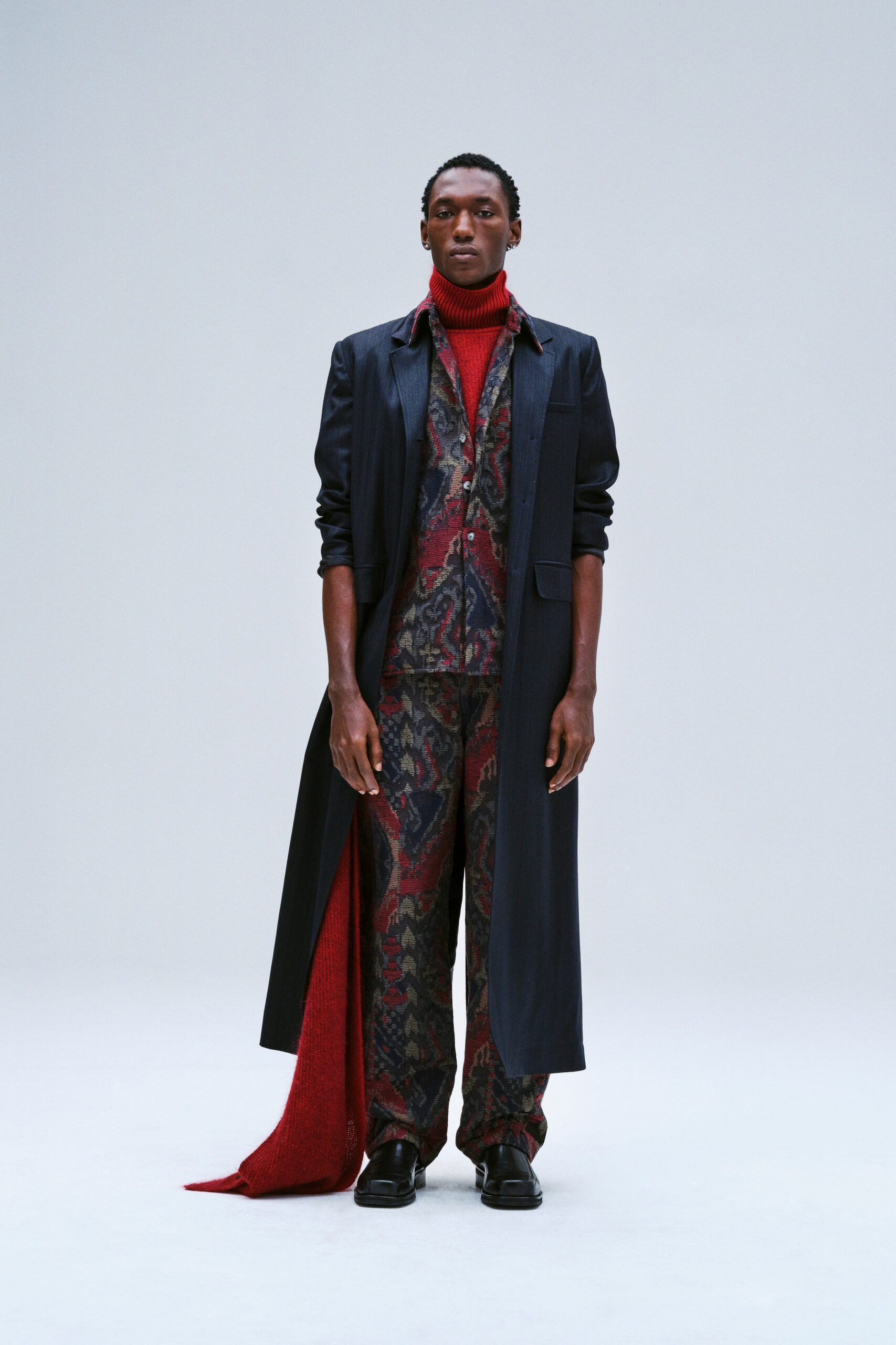 A fitted black coat layered over a printed suit with a collared neckline and long sleeves.