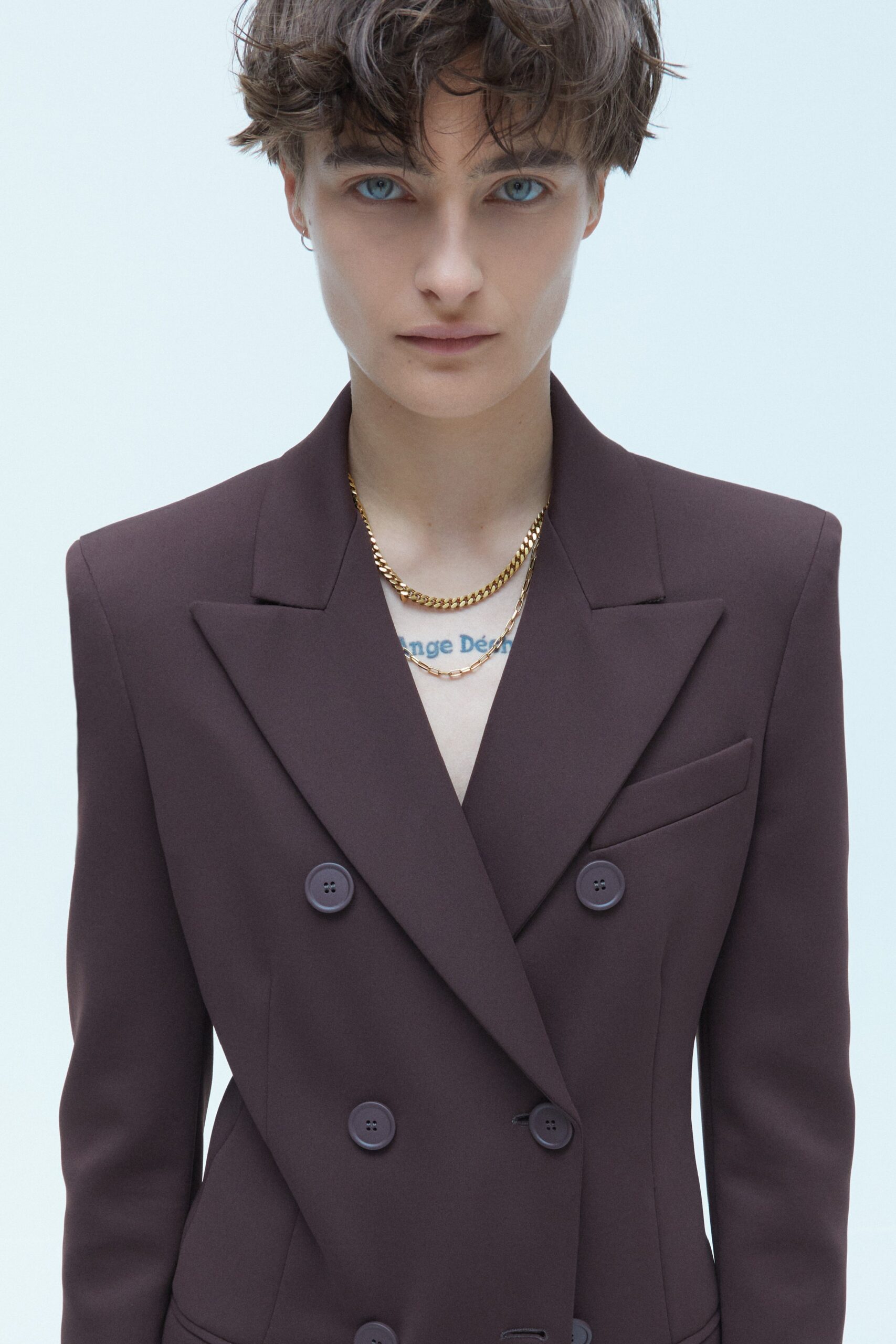 A fitted burgundy cotton blazer with long sleeves and a collared design, featuring button details.