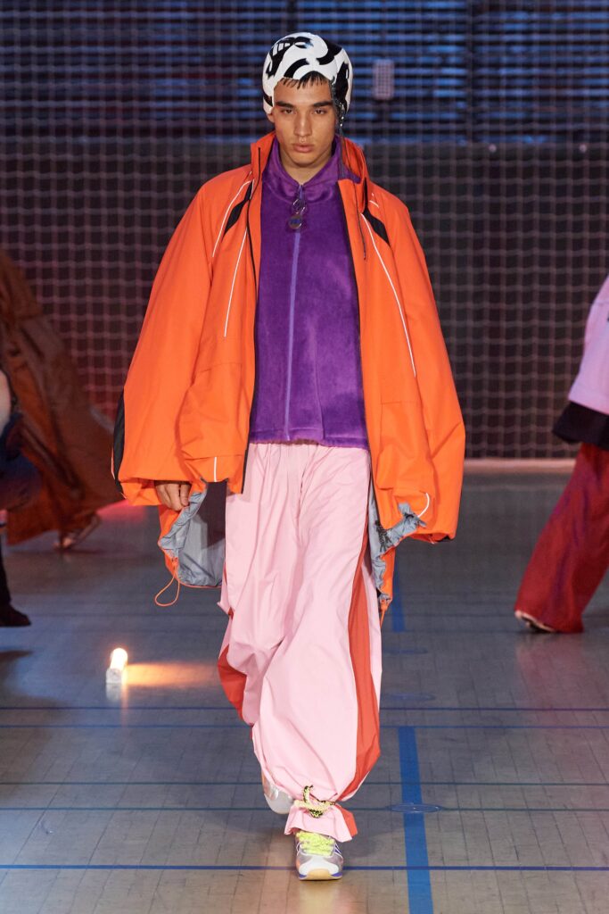 A relaxed fit orange jacket paired with pink pants, featuring a layered design.