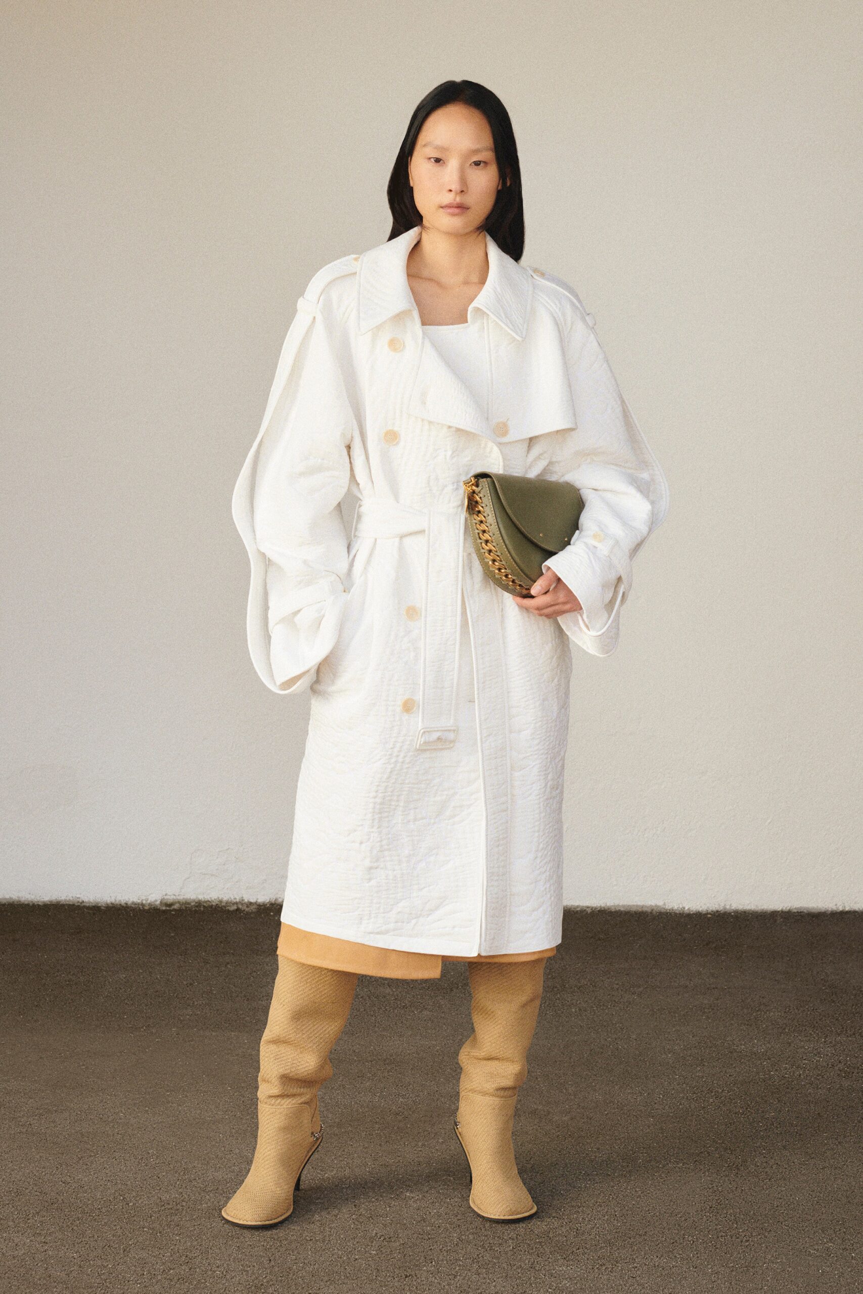 A relaxed white cotton coat with long sleeves and a collared design, featuring button details.