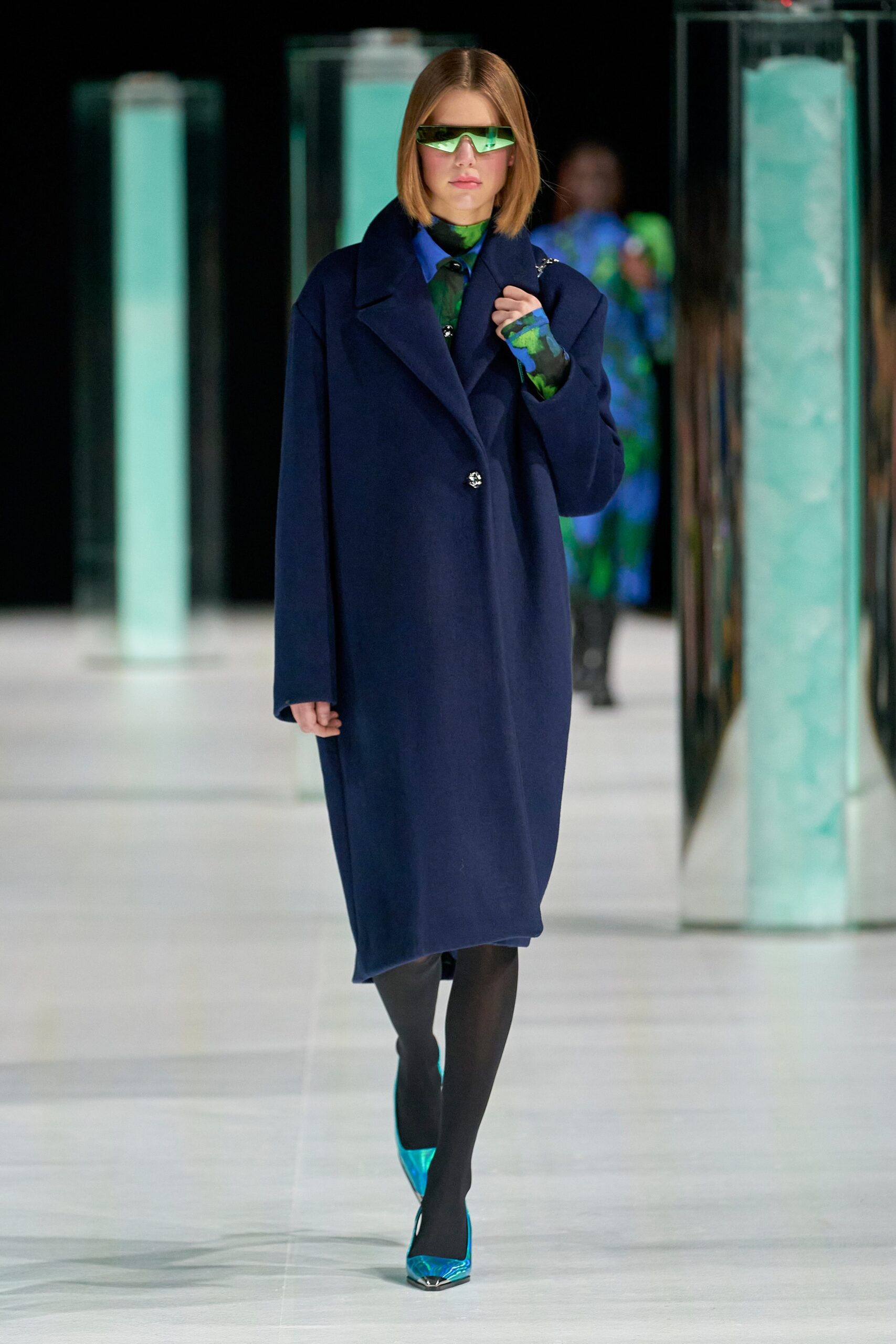 An oversized blue wool coat with long sleeves and a collared design, featuring a button closure.