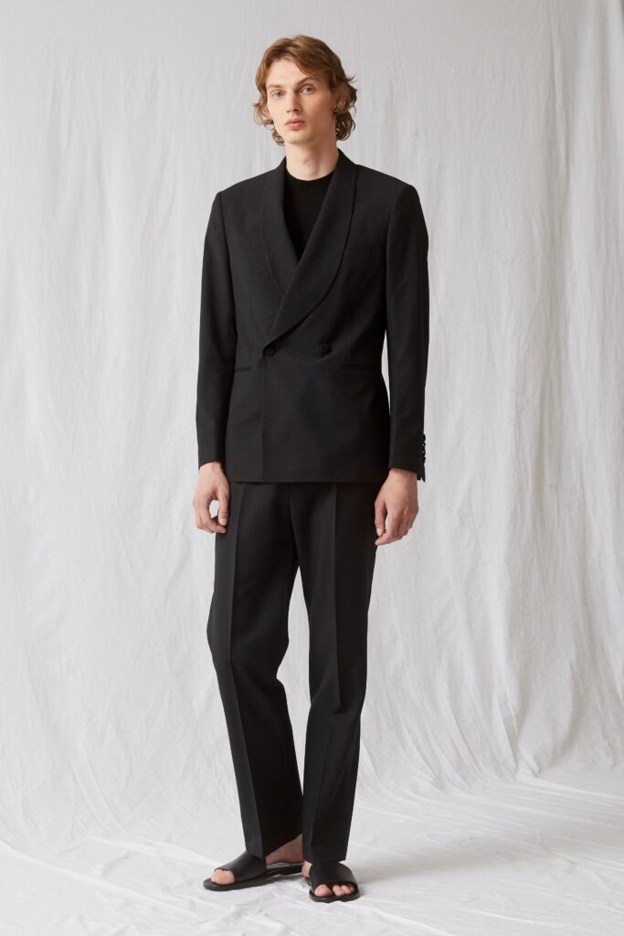 A tailored black suit with long sleeves and a collared design, featuring buttoned details.