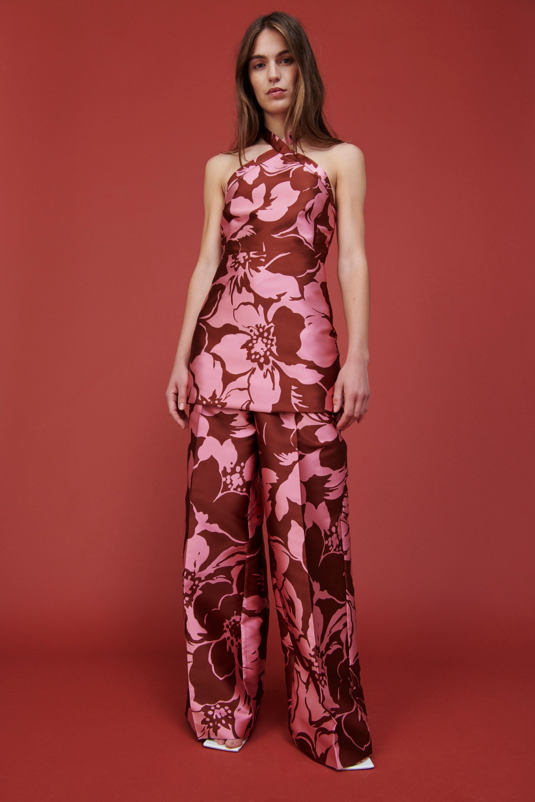 A fitted pink and brown floral jumpsuit with a sleeveless design and flared legs.