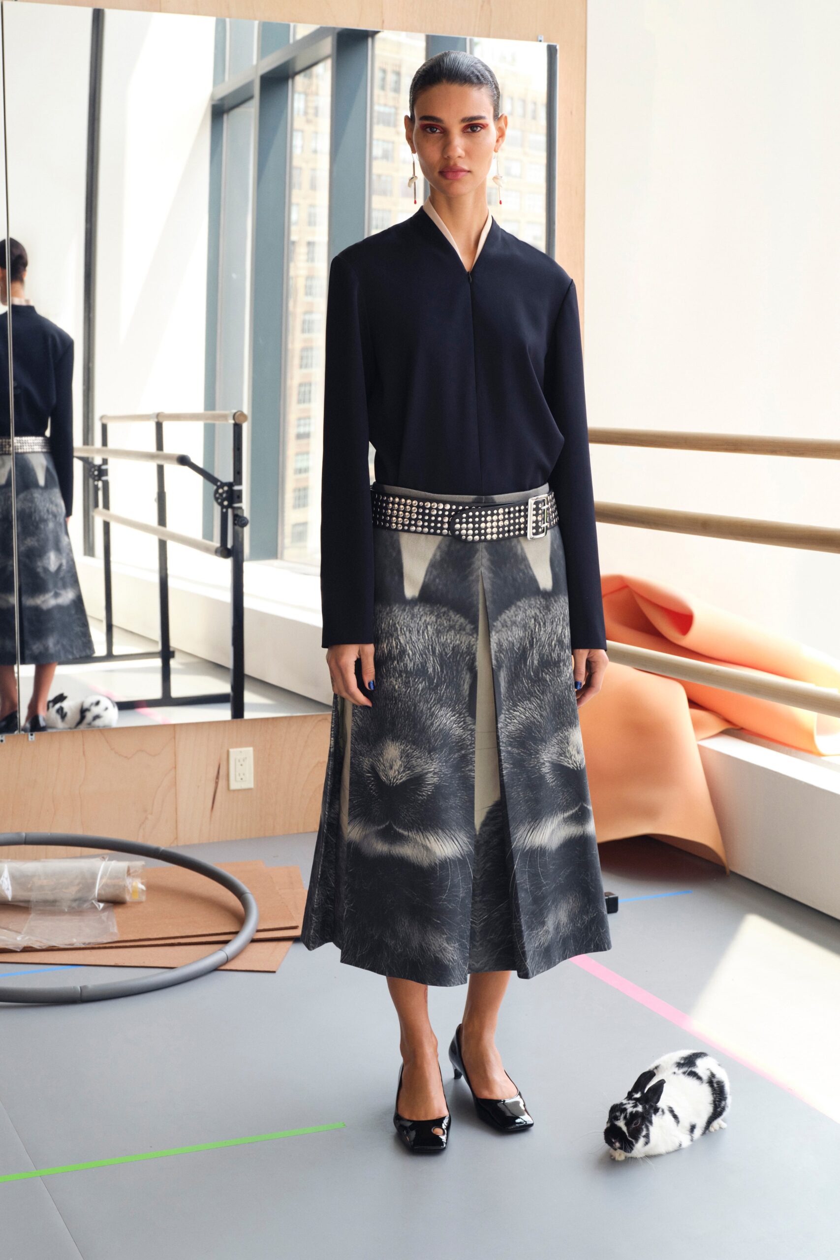 A fitted black blouse with long sleeves paired with a printed gray skirt.