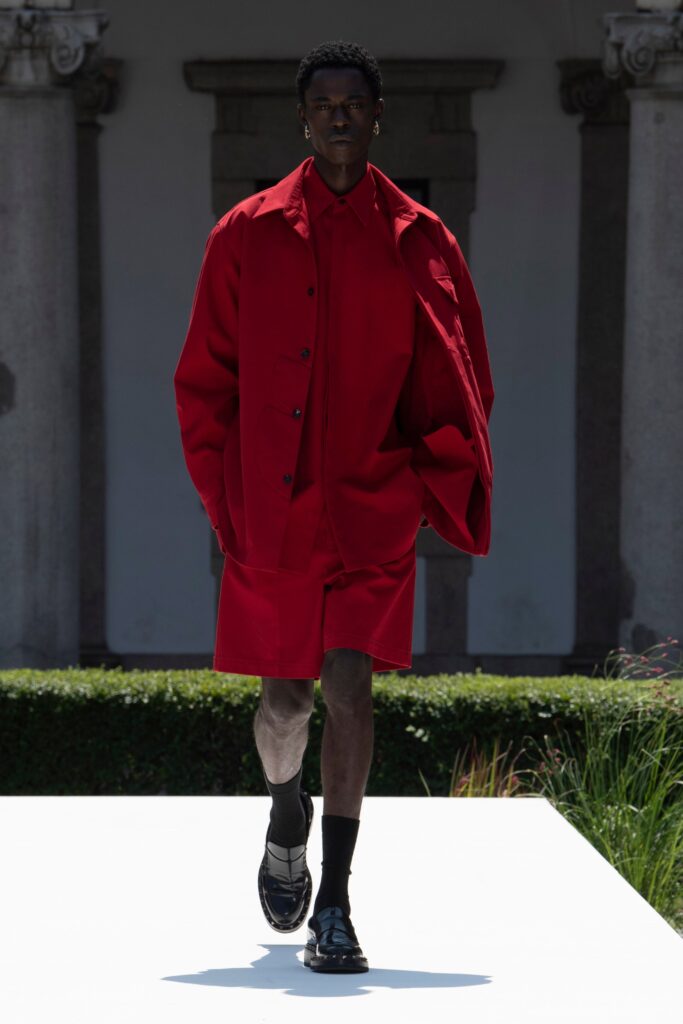 An oversized red cotton jacket paired with matching shorts, featuring a collared design and buttoned details.