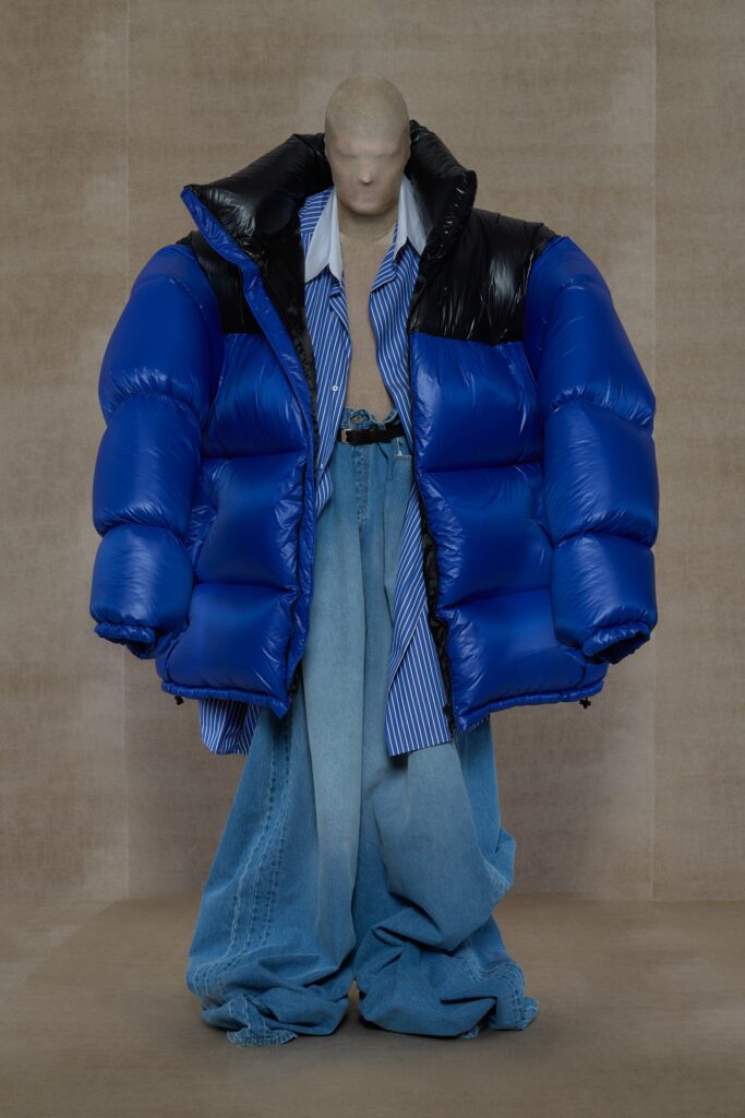 An oversized blue jacket paired with wide-leg denim pants, featuring a collared shirt underneath.