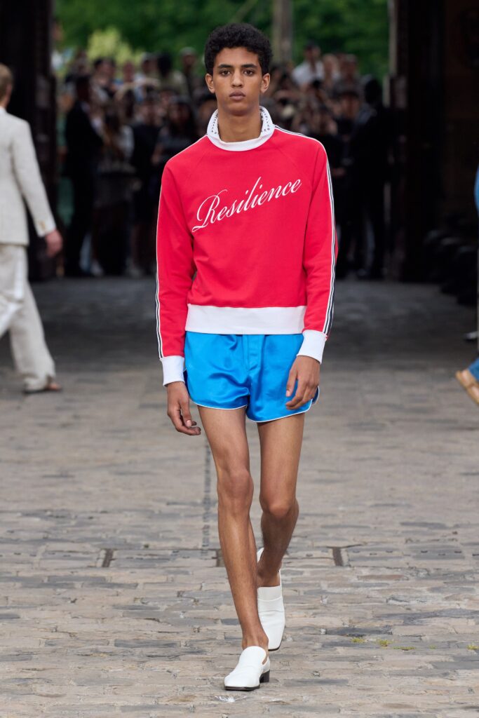A fitted red printed sweater paired with blue shorts for a stylish summer look.