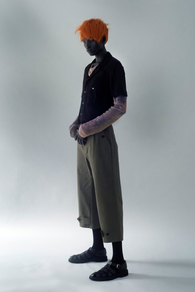 A relaxed black cotton short-sleeve shirt paired with wide-leg green pants.