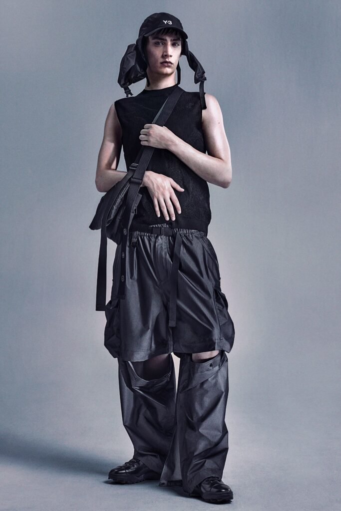 A relaxed black sleeveless top paired with high-waisted layered pants.