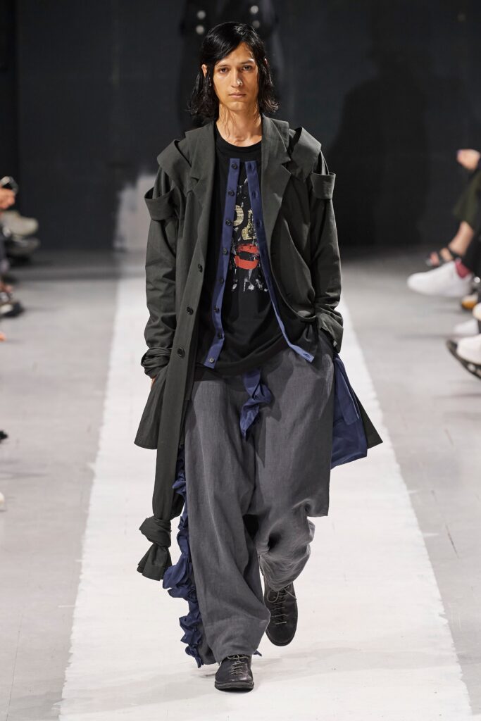 A relaxed black coat paired with gray pants, featuring a layered design.