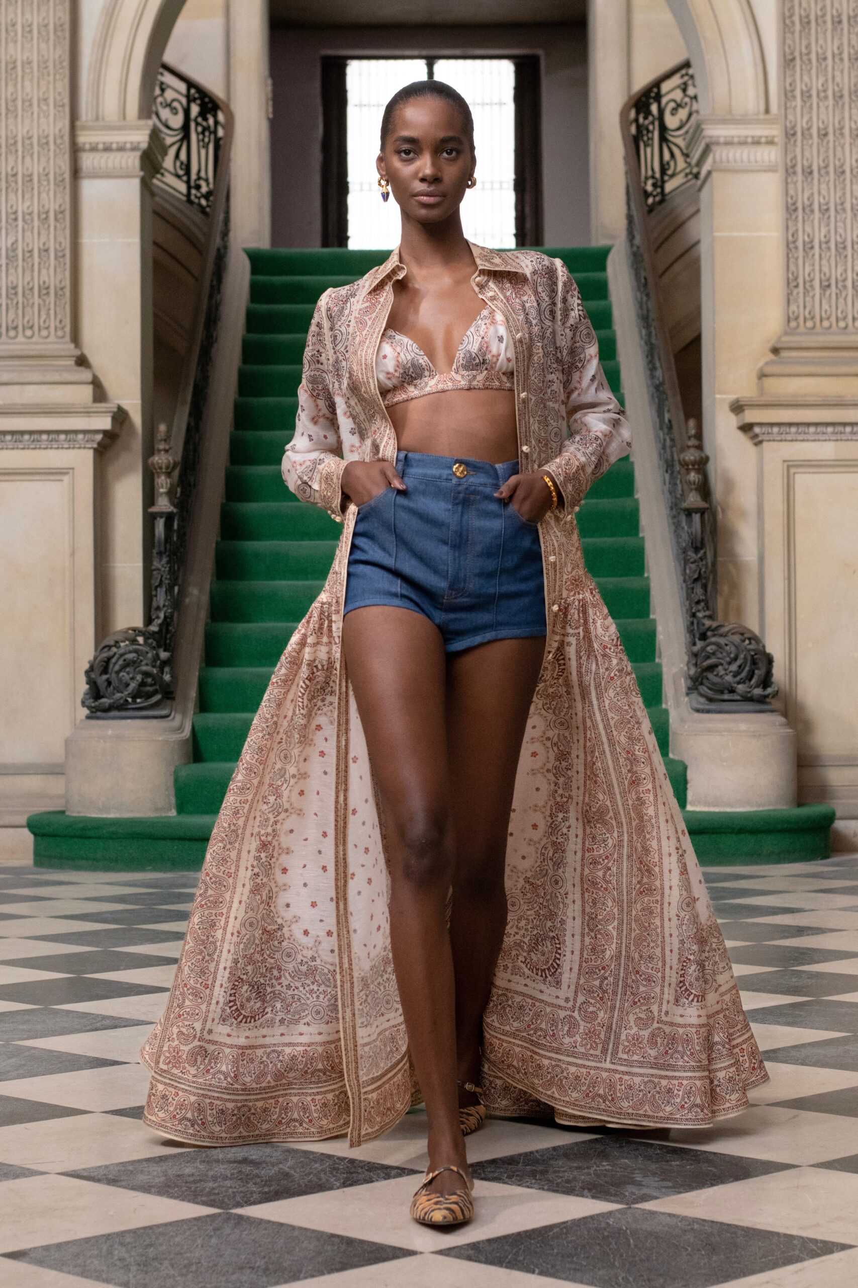 A fitted beige printed silk dress with a collared design and denim shorts.