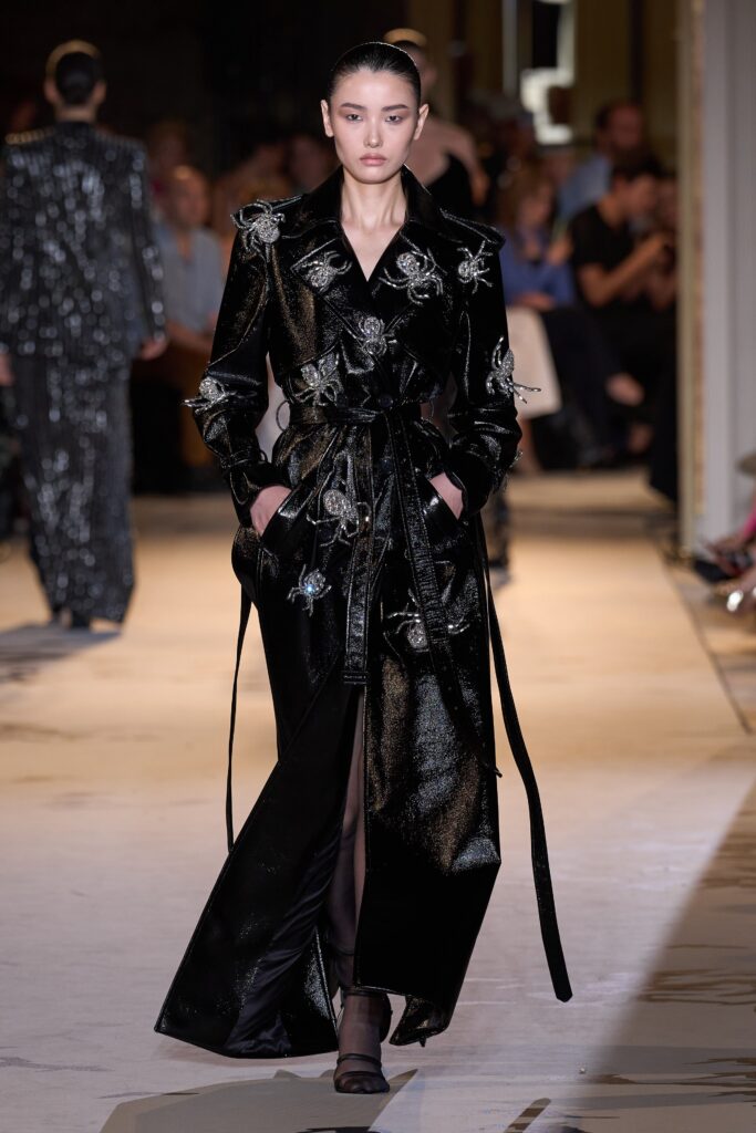 A fitted black silk dress with long sleeves, a collared neckline, and embroidered details.